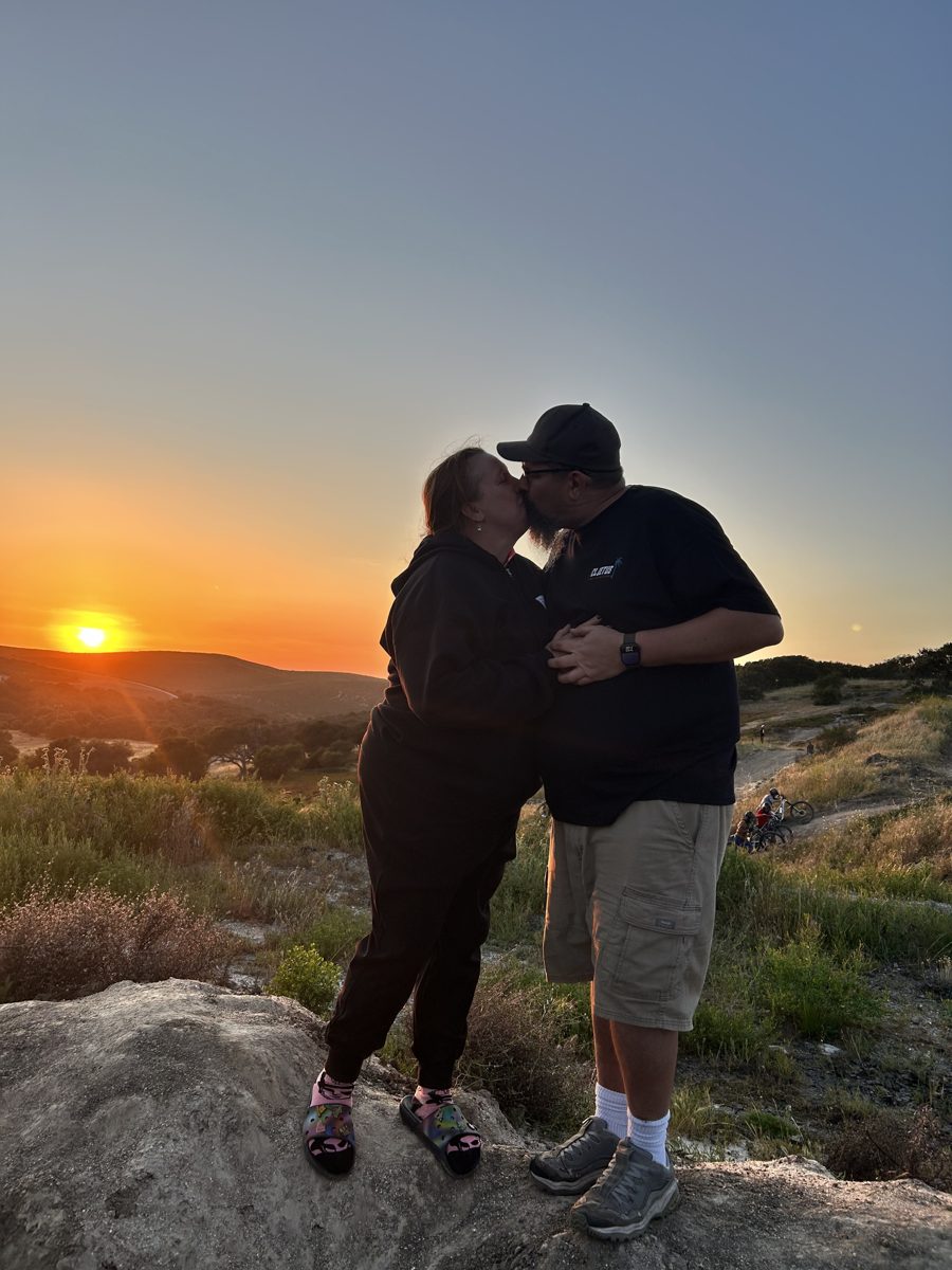 Jen and Sean sharing a kiss with the sun setting behind them
