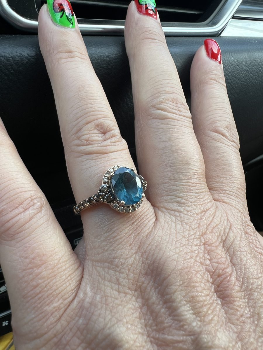 Close-up of Jen's engagement ring, a blue oval stone with a halo of small diamonds